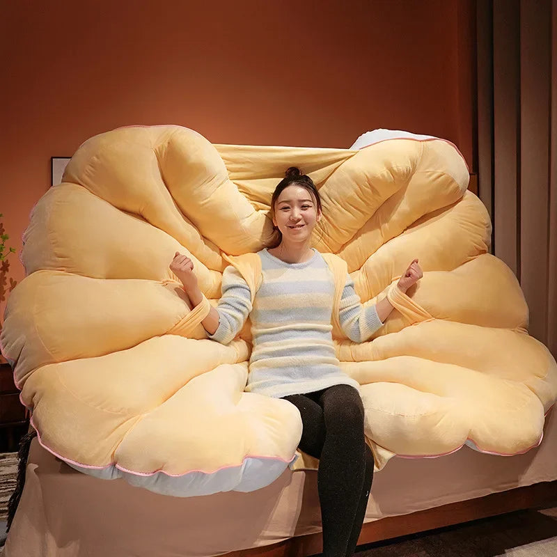 Large seashell-shaped plush cushion from MC The Black Diamond, designed as a giant clam shell pillow for kids' beds.
