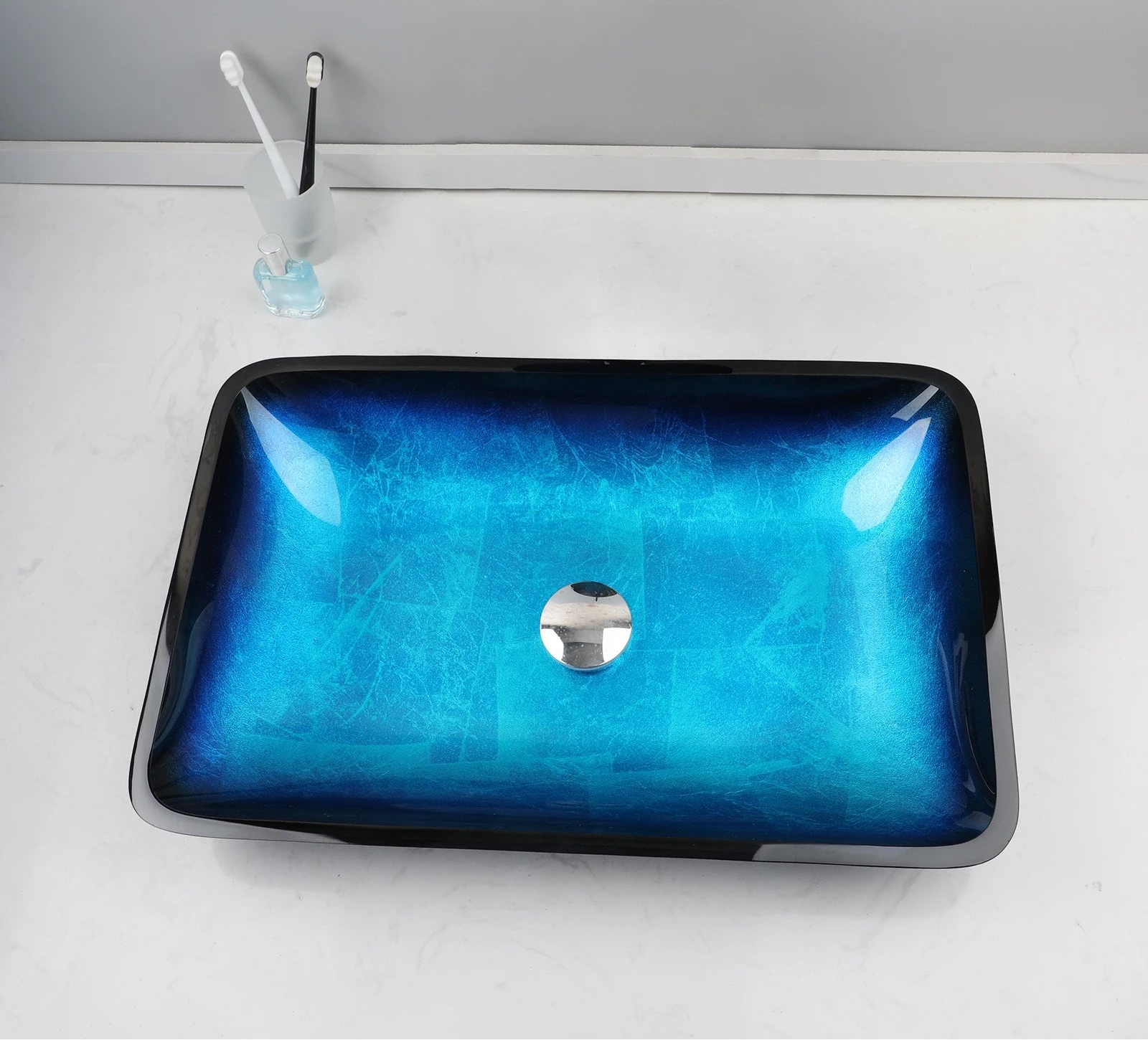 MC THE BLACK DIAMOND ZAPPO tempered glass bathroom vessel sink with waterfall black faucet and oval blue basin above counter.