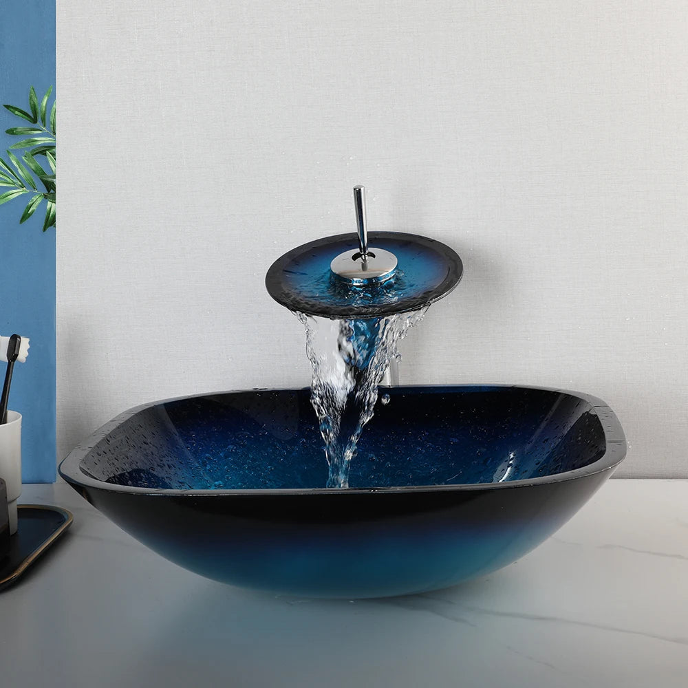 MC THE BLACK DIAMOND ZAPPO tempered glass bathroom vessel sink with waterfall black faucet and oval blue basin above counter.