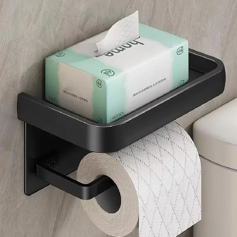 Black gold toilet paper holder by MC THE BLACK DIAMOND mounted on a bathroom wall with a roll of toilet paper in place.